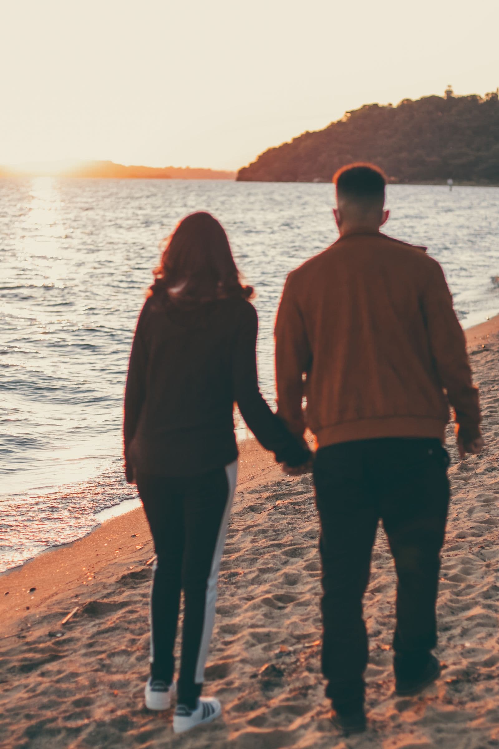Casal caminhando de mãos dadas ao entardecer